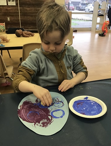 Preschool child decorating egg with paint