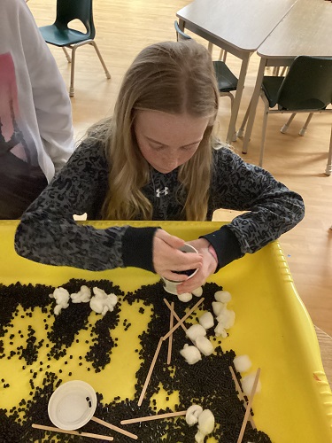 School-age girl making coffee with loose parts