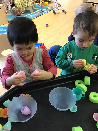 Toddlers exploring plastic eggs