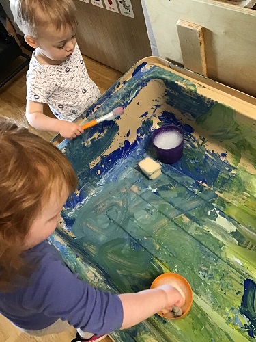 Two children painting the inside of the sensory bin