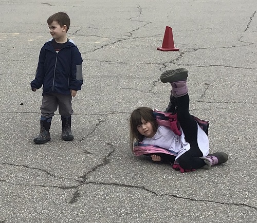Children outside on the black top playing a body movement game