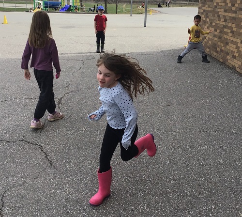 Children outside on the black top playing a body movement game