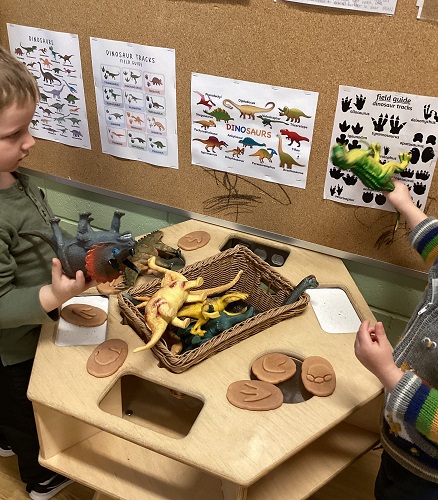Children comparing toy dinosaurs to the posters on the wall