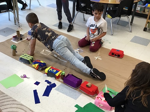 Children adding to their recycled city paper on the floor