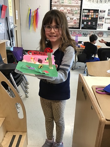 A child holding her creation out of recycled materials