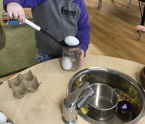 A child using plastic eggs in the kitchen centre