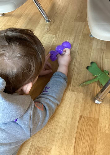 A child on the floor looking a plastic egg with letters on it