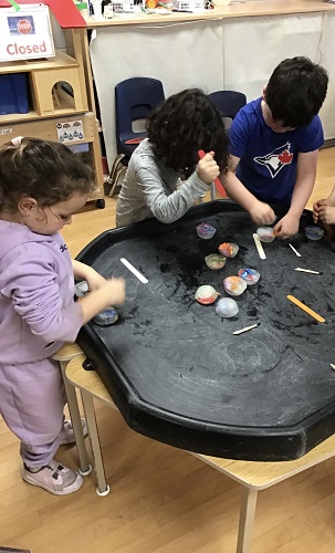 A group of children using wooden sticks to try and break small pucks of ice