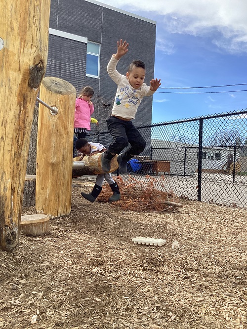 A school age child jumping off the climber