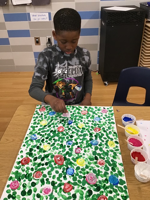 A school age child painting on a canvas