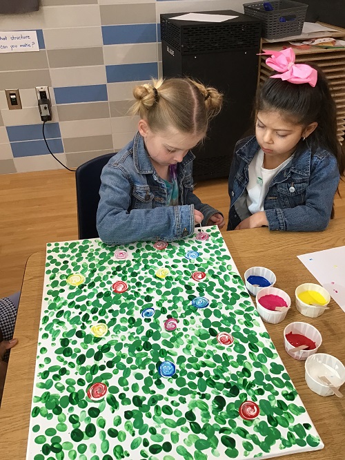 2 school age children painting on a canvas