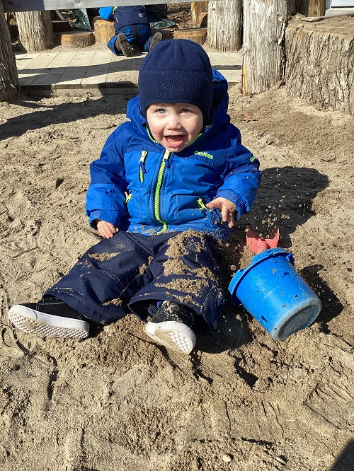 An infant child sitting in the sand box