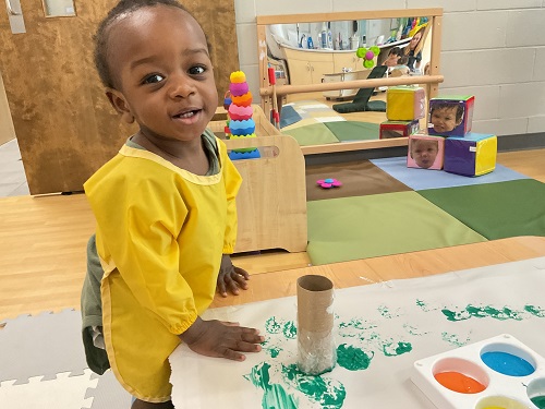 baby in yellow iwth green paint