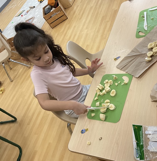 child cutting banana
