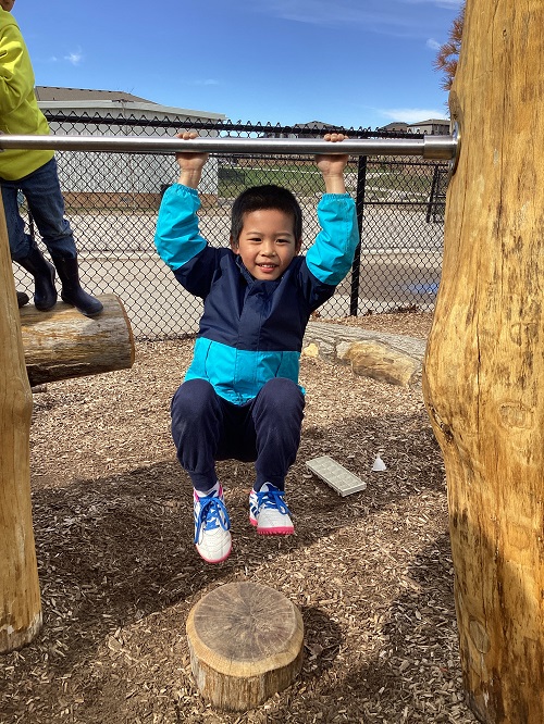 A school age child swinging on the climber