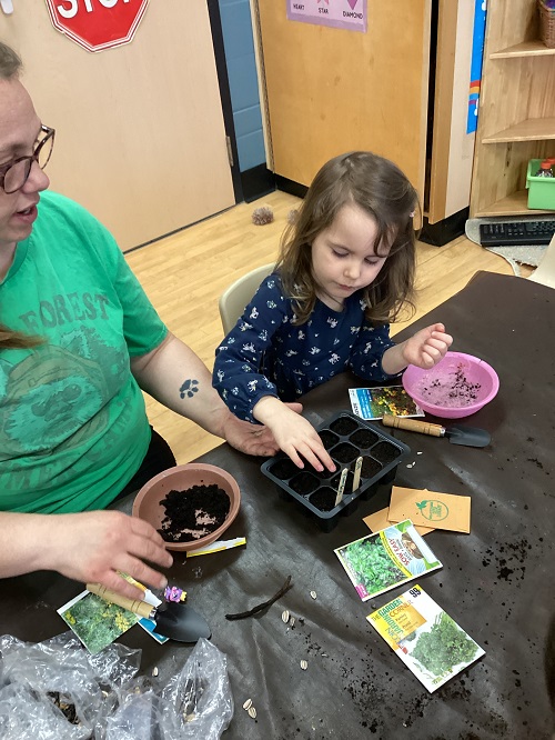 educator and a child planting seeds
