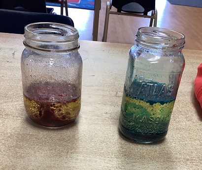 two glass jars with oila nd food colouring in them
