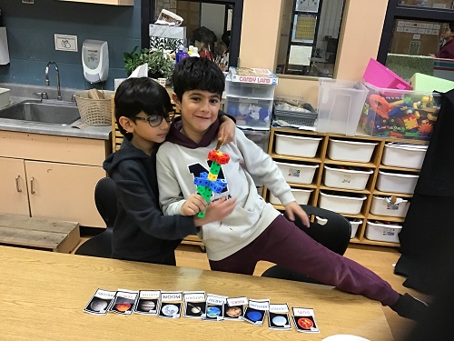 two children showcasing their creation with planets