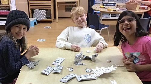 three children sitting around a table with modelling clay