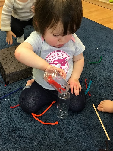 child putting object in bottle