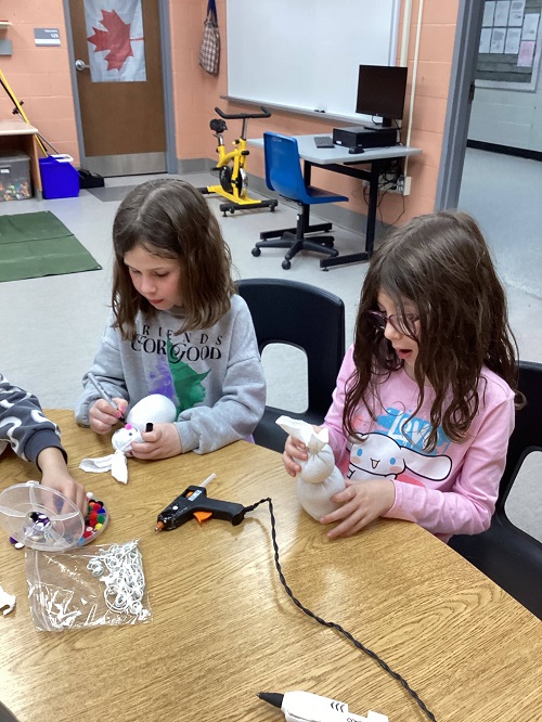 2 children using a hot glue gun to create their bunny