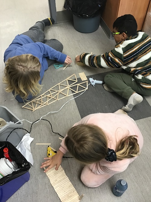two children building their bridge out of loose parts