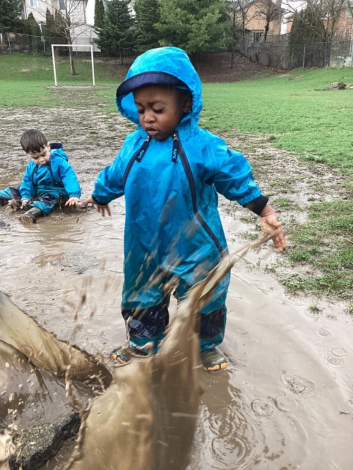 child jumping in a muddy puddle