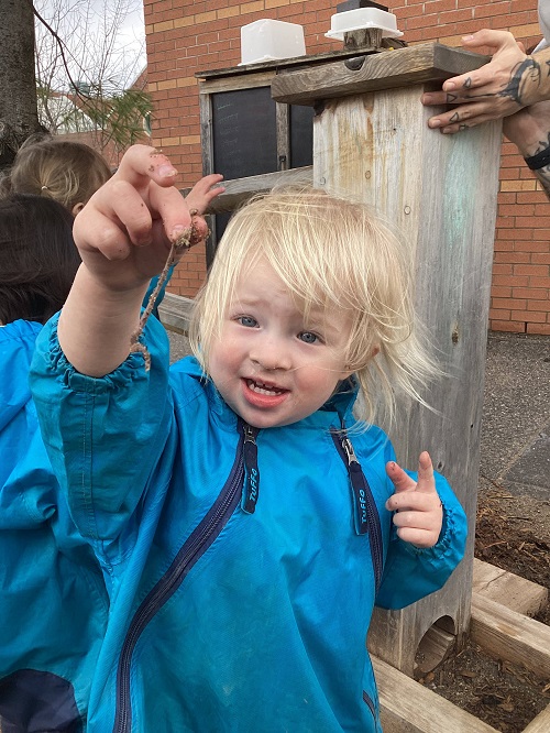 child holding up a worm in their hands