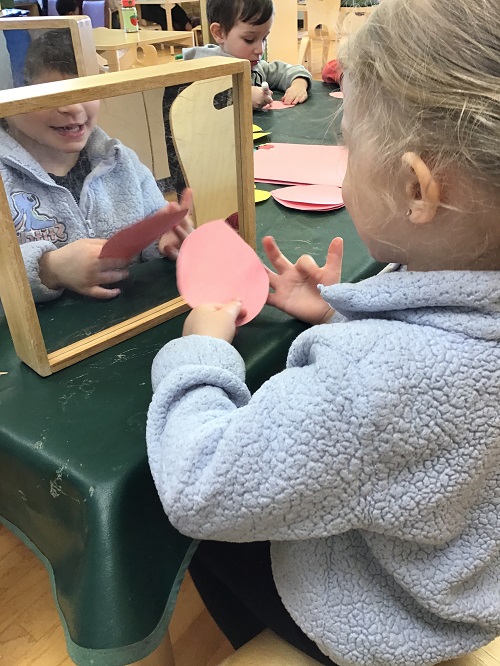 Child looking at their reflection in a mirror.