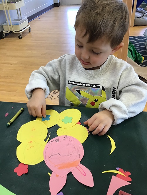 Child putting stickers on a yellow circle.