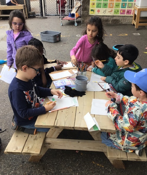 Children colouring on the picnic table outside.