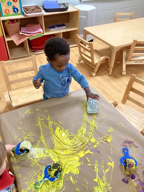 Child driving a car over the yellow paint.