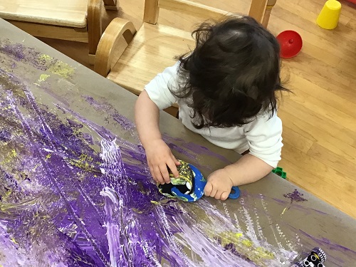 Child feeling the patterns on the paint roller with their fingers.