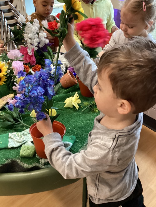 Preschool children putting artificial flowers into pots