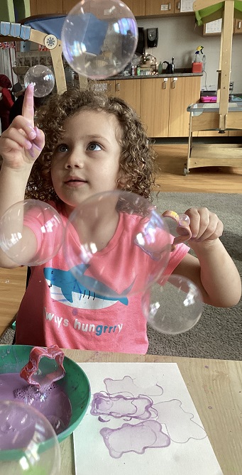 A preschool child popping a bubble