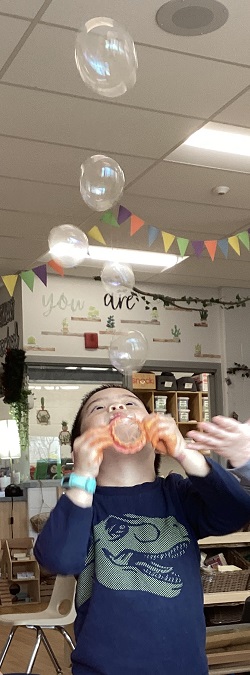A preschool child looking up at bubbles