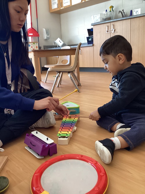 A toddler and educator exploring a xylophone