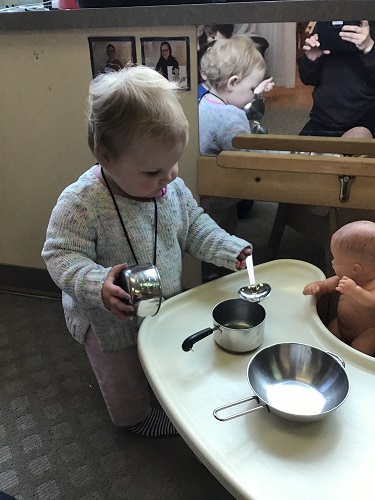 An infant feeding her doll