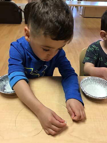 A preschool child adding beads to a string to make a spectial bracelet to represent a Kada