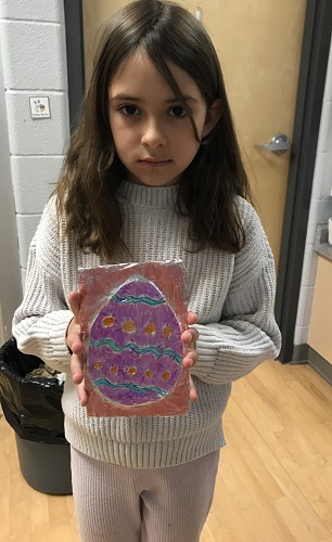 A school aged child holding their foil Easter egg creation