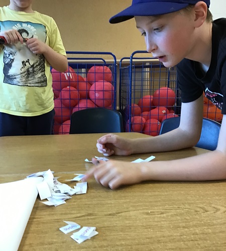 A school aged child choosing slips of paper for a creative story writting activity