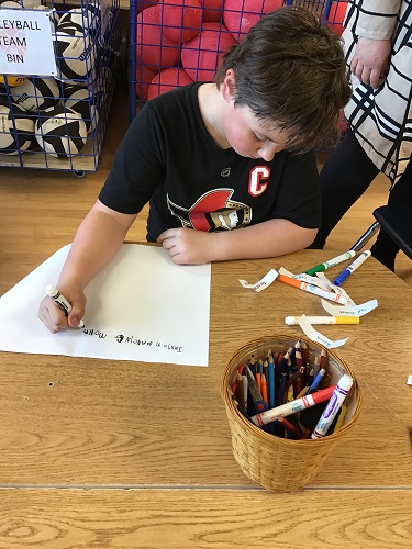 School aged child writting a story using prompting words on slips of paper